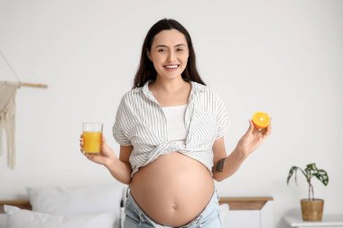 Yatak odasında portakal suyu ve meyve suyu olan hamile bir kadın.
