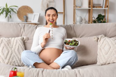 Genç hamile kadın kanepe evde sebze salata yemek