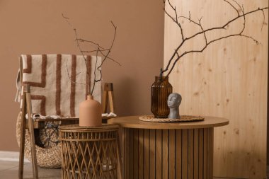 Oturma odasının içinde koltuk, tahta tahta tahta ve sehpanın üzerindeki vazolarda ağaç dalları.