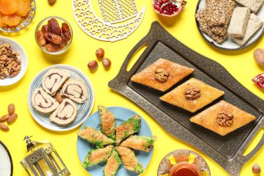 Sarı zemin üzerinde geleneksel Ramazan tatlıları, tasbih ve hilal