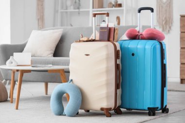 Şık bavulları, seyahat yastıkları ve pasaportlarıyla oturma odasının içinde.