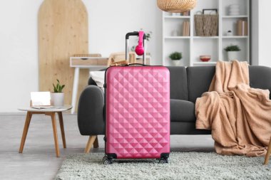 Oturma odasının içinde kanepe, şık bavul ve kulaklıklar var.