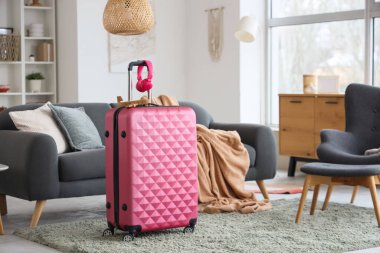 Oturma odasının içinde kanepe, şık bavul ve kulaklıklar var.