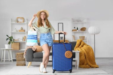 Evinde çanta ve bavuluyla mutlu genç bir kadın.