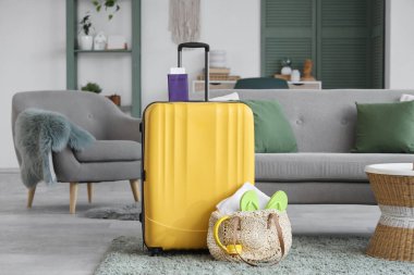 İçinde valiz, pasaport ve yaz aksesuarları olan oturma odasının içinde.