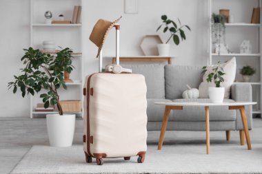 Bavulunda kulaklık ve şapkayla oturma odasının içinde.