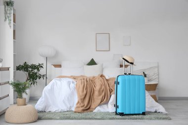 Bavulunda güneş gözlüğü ve yaz şapkası olan yatak odasının içi.