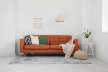 Oturma odasının içinde şık bir deri kanepe, kanepe ve beyaz duvarın yanındaki tabure.