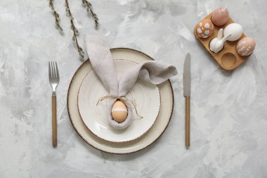 Beautiful table setting with Easter eggs and pussy willow branches on grey background