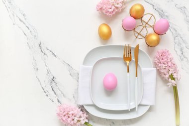 Paskalya yumurtaları ve beyaz arka planda güzel pembe çiçeklerle süslü bir masa.