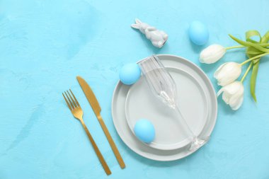 Paskalya yumurtaları, oyuncak tavşancık ve mavi arka planda lale çiçekleri olan güzel bir masa.