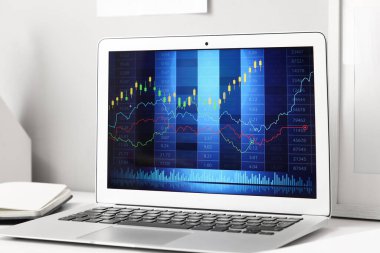 Tüccarın ofisindeki masanın üzerinde döviz kurlarının şeması olan dizüstü bilgisayar, yakın plan.