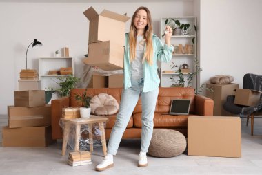 Anahtarı olan ve yeni dairesinde kutuları taşıyan genç bir kadın.