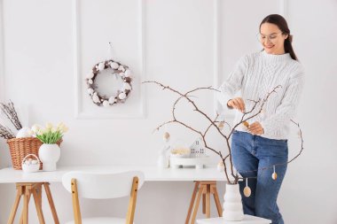 Ofisteki ağaç dallarına Paskalya yumurtası asan genç bir kadın.