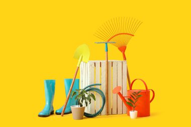 Bahçe malzemeleri, beyaz tahta kutu ve sarı arka planda bitkiler.