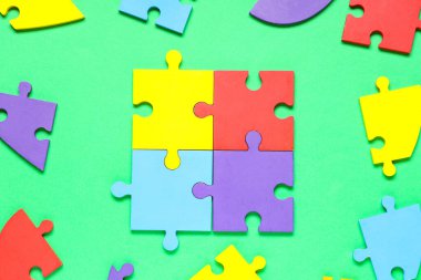 Yeşil arka planda bir sürü renkli yapboz parçası var. Otistik bozukluk kavramı