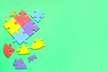 Yeşil arka planda bir sürü renkli yapboz parçası var. Otistik bozukluk kavramı