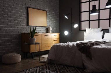 Geceleri rahat yatağı ve parlak lambaları olan modern yatak odasının içinde.