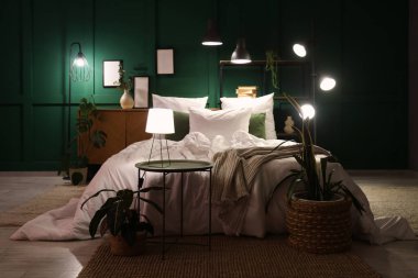 Şık bir yatak odası, rahat bir yatak odası, çiçekler ve geceleri parlayan lambalar.