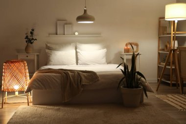 Şık bir yatak odası, rahat bir yatak ve geceleri parlayan lambalar.