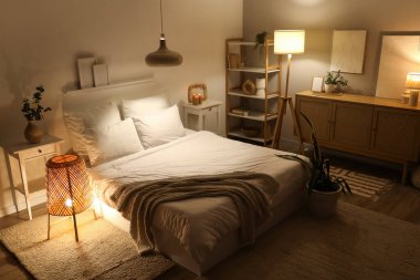 Şık bir yatak odası, rahat bir yatak ve geceleri parlayan lambalar.