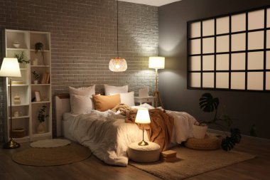 Geceleri rahat yatağı ve parlak lambaları olan modern yatak odasının içinde.