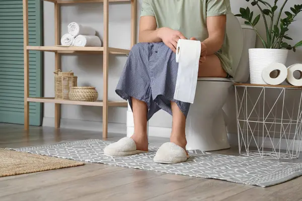 Tuvaletteki klozete kağıt rulo yapıştırmış bir adam.