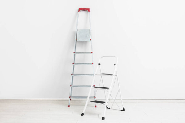 Maintenance ladders near white wall