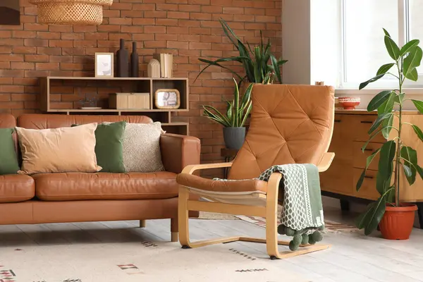 Deri kanepesi, koltuğu, çiçekleri ve pencerenin yanındaki raf ünitesi olan oturma odasının içinde.