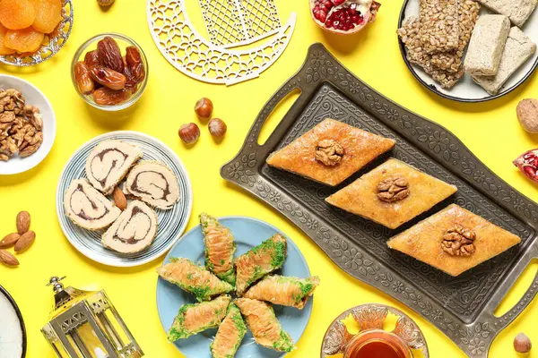 Sarı zemin üzerinde geleneksel Ramazan tatlıları, tasbih ve hilal