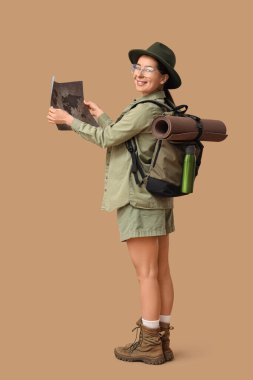 Genç bayan turist, bej arka plan haritasını inceliyor.