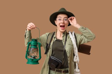 Bej arka planda feneri olan mutlu genç bayan turist.