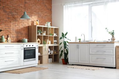 Beyaz tezgahlı, fırınlı ve raflı şık bir mutfak.