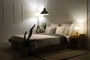 Şık bir yatak odası, rahat bir yatak odası, çiçekler ve geceleri parlayan lambalar.