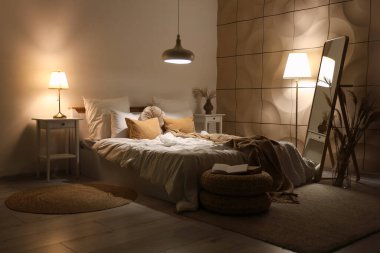 Geceleri rahat yatağı, aynası ve parlayan lambaları olan şık bir yatak odası.