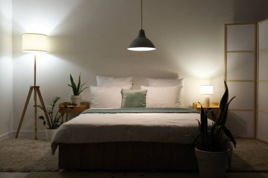 Şık bir yatak odası, rahat bir yatak odası, çiçekler ve geceleri parlayan lambalar.