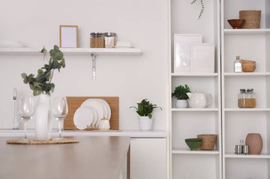 Beyaz tezgahlı, masa ve raf üniteli şık bir mutfak.