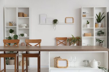 Ada masası, ev bitkileri ve raf üniteleri olan şık bir mutfak.