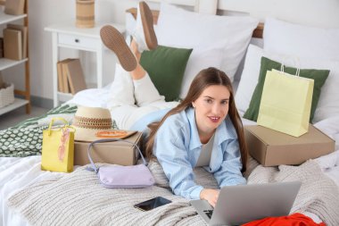 Dizüstü bilgisayarı, alışveriş çantaları ve yeni moda kıyafetleri olan mutlu bir moda blogcusu.