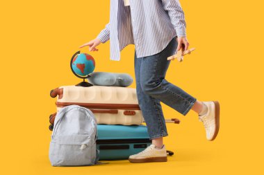 Çantalı genç bir kadın, sırt çantası, küre ve sarı arka planda ahşap bir uçak, yakın plan. Seyahat kavramı