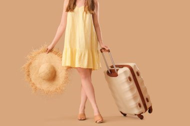 Bavulu ve bej arka planda hasır şapkalı genç bayan, yakın plan. Seyahat kavramı