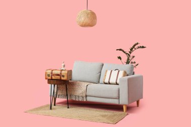 Şık gri kanepe, sehpa ve pembe arka planda eski bavullar.