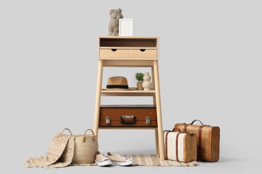 Gri arka planda şapka, dekor ve klasik bavullu şık makyaj masası.