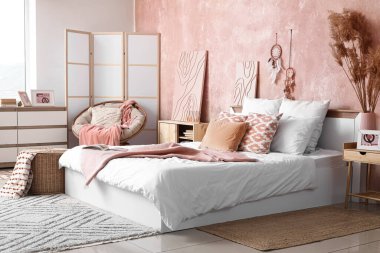 Şık bir yatak odası, rahat bir yatak odası ve komodinin üzerinde otlar.