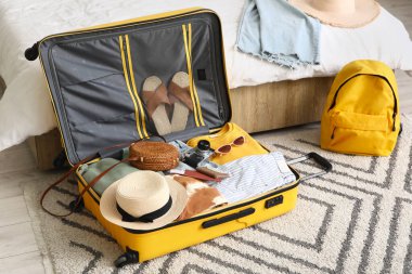 Otel odasında giysiler ve seyahat aksesuarlarıyla dolu bavulları boşalttım.