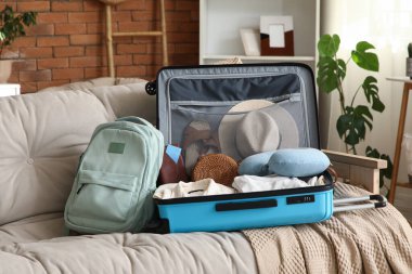 Oturma odasındaki kanepede giysiler ve aksesuarlarla dolu bavulları boşalttım.