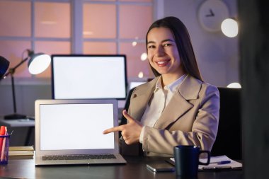 Ofisinde boş dizüstü bilgisayarı olan genç bir iş kadını.