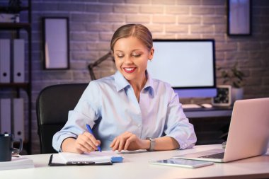 Genç iş kadını geceleri ofiste yazıyor.