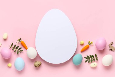 Yumurta şekilli boş kart, Paskalya yumurtaları, dekoratif havuçlar ve pembe arka planda yeşil yapraklar.