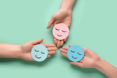 Yeşil arka planda kağıt tebessümleri olan kadın eller. Dünya Sağlık Günü